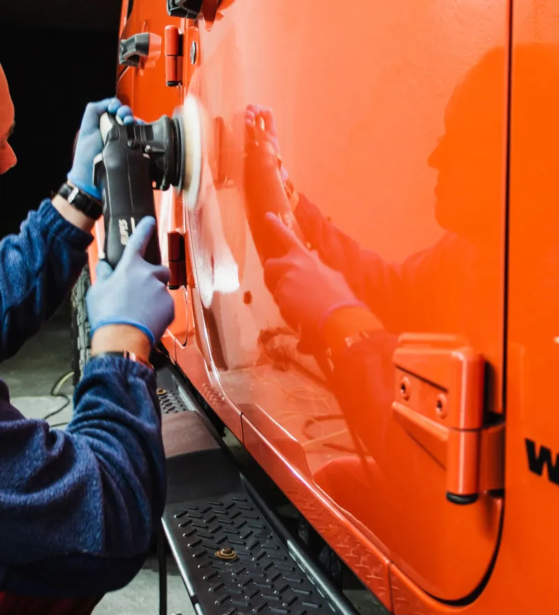 Glossy orange SUV door after machine polishing